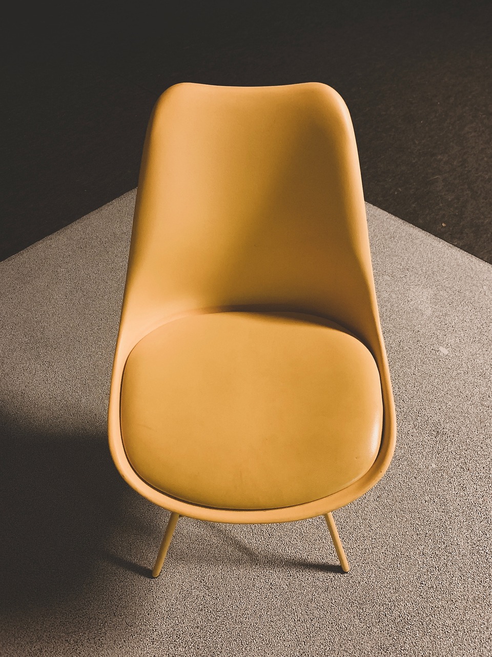 Orange velvet armchair in a brick-walled room with an abstract painting
