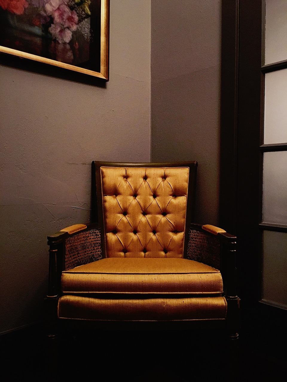 Tufted golden-orange velvet armchair in a dim corner
